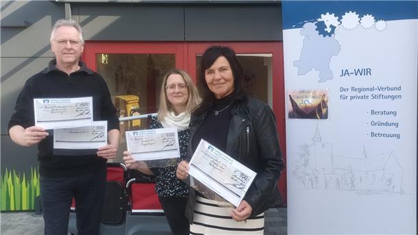 Hilko Schütte, Vorstandsmitglied der Jade-Wirtschaftsraum-Regionalstiftung, vergibt die Schecks an die Leiterin des Kindergartens, Frau Katja Hofschildt und an Frau Sandra Janßen, zweite Vorsitzende des Shantychors, die Hafenperlen.