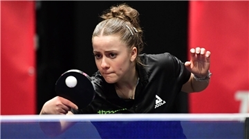 Eine Tischtennisspielerin schiebt den Ball über das Netz.