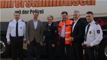 Fünf Männer und in der Bildmitte eine Frau stehen vor einem Lkw mit der Aufschrift "Fernfahrerstammtisch der Polizei".