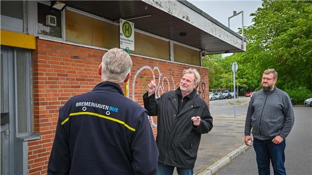 Holger Welt (Mitte) und Claus Altenburg vom SPD-Ortsverein diskutieren mit Busfahrern über den verrottenden Zustand ihres Aufenthaltsraumes.