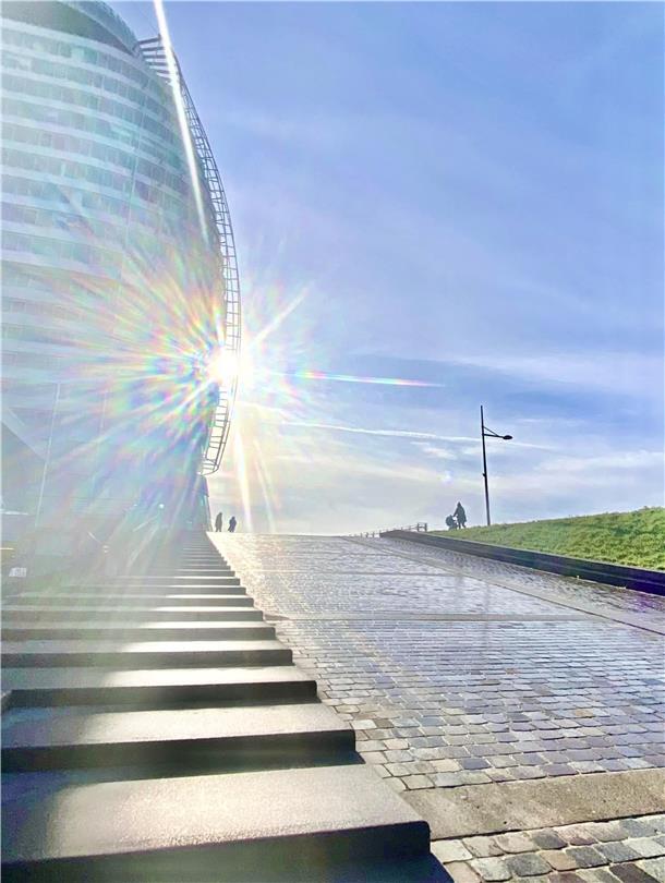 Horizonte. Lichtblicke. Wege. Die Sonne als gleißendes Gestirn über Rampe und Treppe unter dem Bremerhavener Atlantic Sail City hinauf zum Deich hat Symbolkraft.
