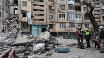 Hundeführer stehen neben einem Wohnhaus in Odessa, das von einer russischen Drohne zerstört wurde.