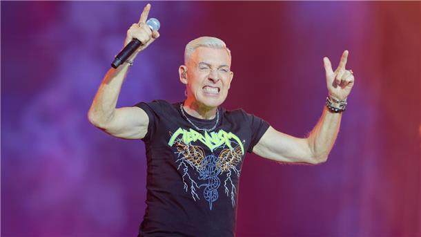 Diese Acts stehen schon für das Deichbrand-Festival 2026 fest Ein Sänger mit kurzen, blondierten Haaren steht auf der Bühne und hält ein Mikrofon in der Hand. H.P. Baxxter von der Band Scooter.