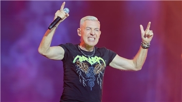 Ein Sänger mit kurzen, blondierten Haaren steht auf der Bühne und hält ein Mikrofon in der Hand. H.P. Baxxter von der Band Scooter.