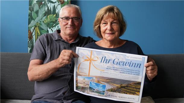 Ein Mann und eine Frau halten einen Gutschein in der Hand.