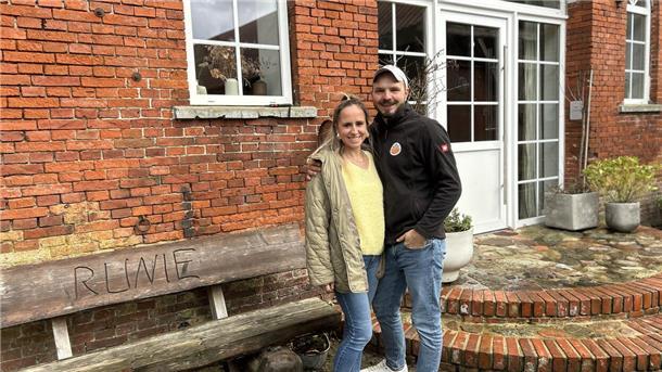 Eine Frau und ein Mann stehen vor einem roten Backsteingebäude.