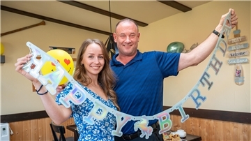 Spenderin Malin Fleischauer und Empfänger Jeff Bettez halten eine Girlande hoch: Happy Birthday