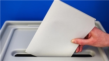 Ein Wahlzettel verschwindet in der Urne.