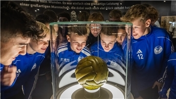 Eine junge Fußballmannschaft bestaunt einen aufgebahrten Ball im Museum.