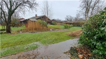 Im Hintergrund das Haus von Marita Manzi mit dem nassen Garten. Im Vordergrund der nasse Fußweg zum Haus ihres Nachbarn. 