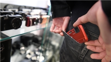 Eine Hand steckt ein Smartphone in die hintere Hosentasche. 
