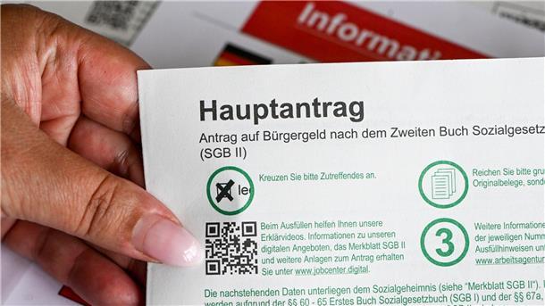 Bildungsanbieter kritisiert Jobcenter Im Jobcenter hält eine Frau einen Antrag auf Bürgergeld in der Hand.