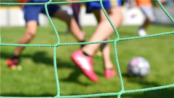 Kinder spielen auf einem Sportplatz Fußball.