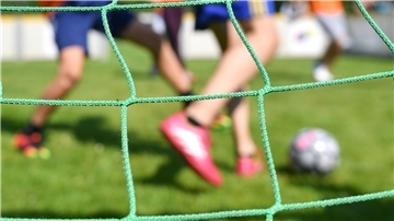 Kinder spielen auf einem Sportplatz Fußball.