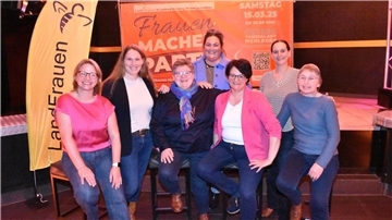 Frauen vor einem Werbebanner.