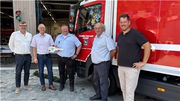 Fünf Männer stehen vor einem roten Einsatzfahrzeug der Freiwilligen Feuerwehr Loxstedt. Einer von ihnen hält symbolisch einen großen weißen Schlüssel in der Hand.
