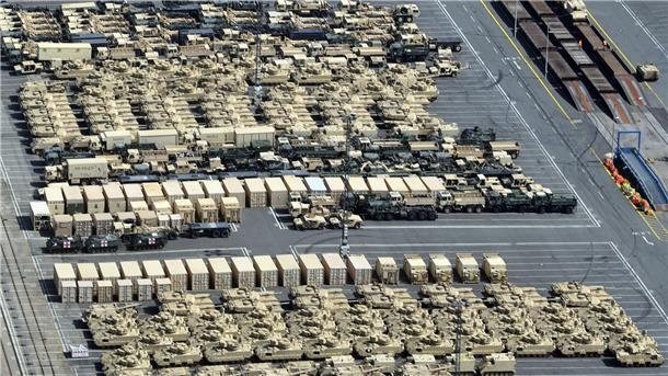 US-Panzer und Lkw auf einer Hafenfläche.