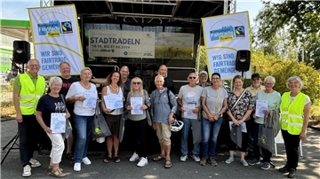 16 Frauen und Männer stehen nebeneinander vor einer Bühne. Einige halten Urkunden in Händen.