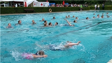 eine Gruppe Kinder schwimmt in einem Freibad