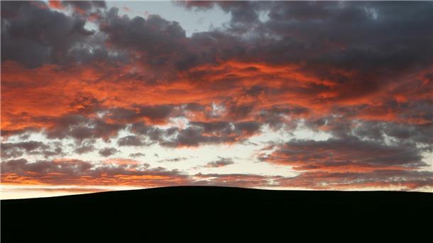 Im Sonnenaufgang leuchten die Wolken rötlich.