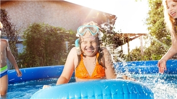 Glückliche Kinder planschen in blauem Wasser eines Swimmingpools. 