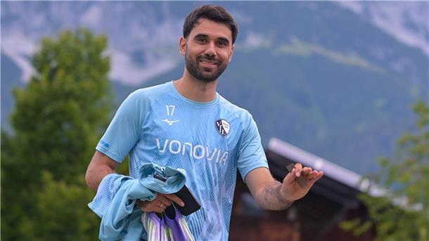 Ein Fußballer lächelt in die Kamera.  