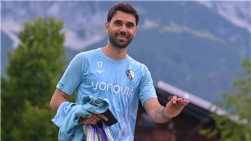 Ein Fußballer lächelt in die Kamera.  