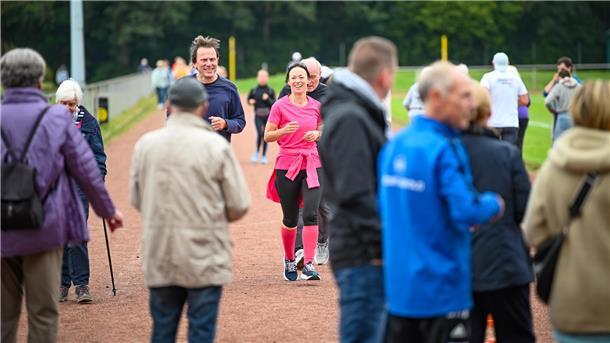 Läufer umrunden einen Sportplatz.