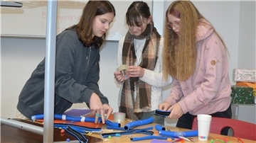 Im Workshop „Energiedomino“ tüfteln Lina Häring (von links), Hanna Behrmann und Ida Wittkowsky an der Frage, wie Energie bestmöglich genutzt werden kann. Zur Veranschaulichung bauen sie eine Murmelbahn.