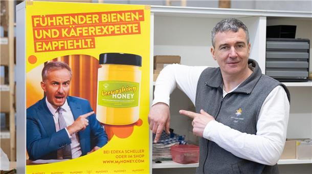 Imker Rico Heinzig neben einem Plakat mit dem Foto des Moderators Jan Böhmermann.