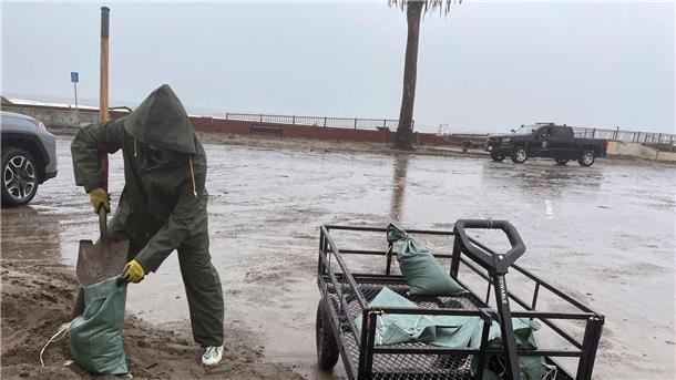 In Aptos schaufelt eine Frau im strömenden Regen Sand in Säcke.
