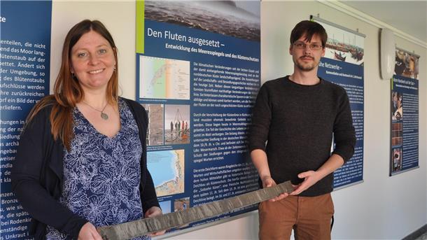 Eine Frau und ein Mann gucken in die Kamera. Sie stehen im Nationalparkhaus Museum Fedderwardersiel.