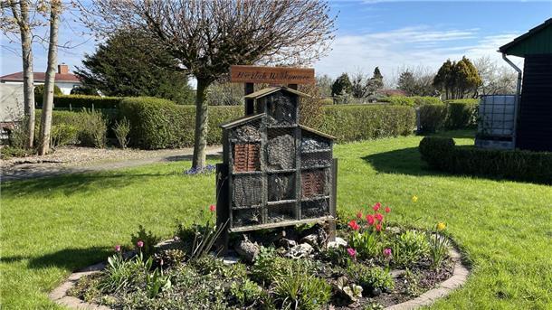 Der Frühling kommt und im Schrebergarten wird ordentlich angepackt Insektenhotel auf grüner Wiese