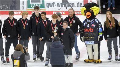 Eishockeyspieler stehen in einer Reihe mit ihrer Medaille um den Hals und einem Pokal in den Händen.