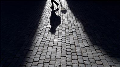 Der Schatten eines Fußgängers ist auf dem Pflaster zu sehen. 
