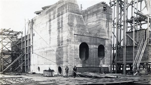 Ein aus Beton gegossenes Bauteil der Schleuse. Davor stehen zwei Männer.