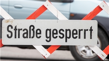 An einer Straßensperre ist ein Schild mit der Aufschrift „Straße gesperrt“ angebracht. 