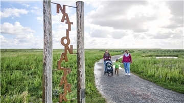 Spaziergänger auf dem Langwarder Groden vor dem Schriftzug „Nationalpark“.