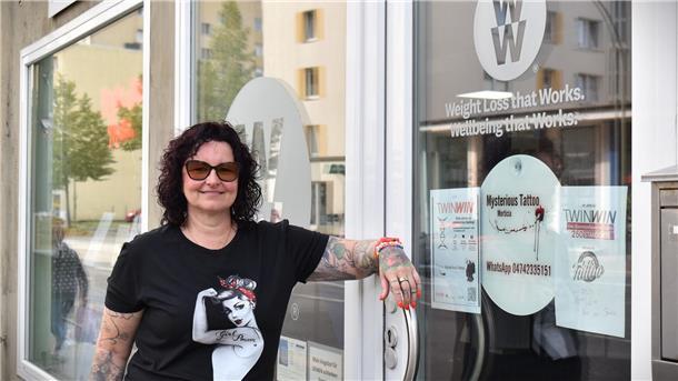 Eine Frau lehnt an einer Tür und lächelt in die Kamera