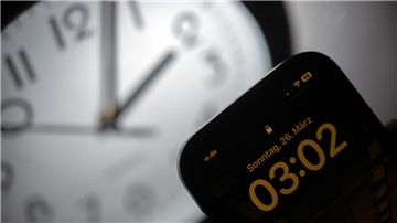 Ein Smartphone zeigt die Uhrzeit «03:03» an, während auf einer analogen Uhr noch 02:03 Uhr ist. Am 26. März werden die Uhren um 02:00 Uhr auf 03:00 Uhr vorgestellt und die Sommerzeit beginnt.