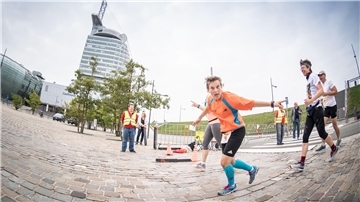Läufer joggen am Vorplatz des Sail-City-Hotels in Bremerhaven vorbei.
