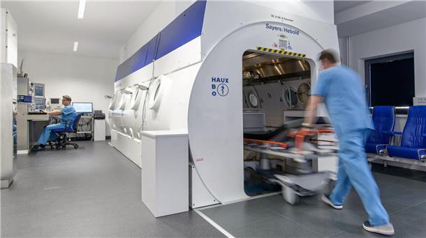Ein Krankenpfleger vor einer  Sauerstoffüberdruckkammer.