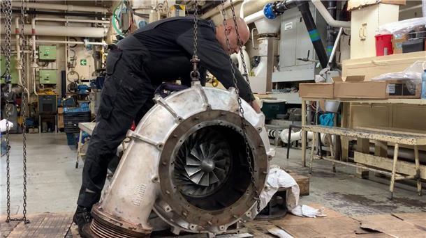 In einer der Werkstätten auf der „Artania“ arbeitet ein Mechaniker an der ausgebauten Verdichterseite eines Turboladers.