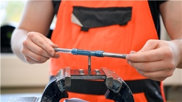 In einer Lehrwerkstatt bohrt ein Auszubildender im 1. Lehrjahr im Rahmen seiner Ausbildung ein Gewinde.