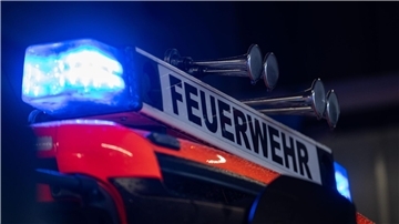 Ein Einsatzfahrzeug der Feuerwehr steht mit Blaulicht bei der Feuerwache (gestellte Szene).