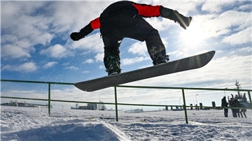 Ein Snowboarder springt im Schnee am Deich in Bremerhaven.