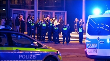 Polizisten stehen während des Einsatzes mit Besuchern vor einem Kino. I