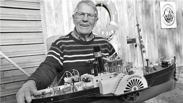 Ein älterer Mann mit einem Schiffsmodell auf einem Schwarz-Weiß-Foto. Kapitän Elmar Hüttenmeister aus Butjadingen ist im Alter von 85 Jahren verstorben.