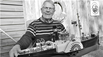 Ein älterer Mann mit einem Schiffsmodell auf einem Schwarz-Weiß-Foto. Kapitän Elmar Hüttenmeister aus Butjadingen ist im Alter von 85 Jahren verstorben.