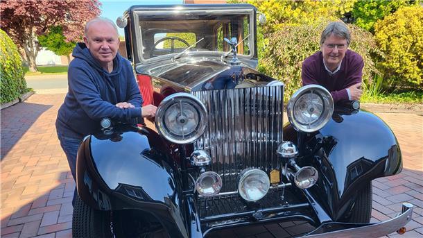 Zwei Männer lehnen sich an einem Oldtimer an. 